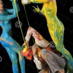 Nude Girls Pouring Color on a Man Sitting on Floor Stock Photo
