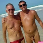 File:Two men on the beach one wearing swimtrunks the other nude.jpg