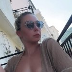 Wife relaxes topless on public balcony.